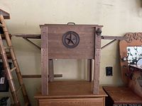 Front view of the wooden Western-themed cooler with star emblem, attached side tables, and mounted beer opener on the right.