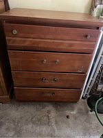 Front view of the fruitwood chest of drawers showing four drawers with metal pulls and visible scratches and wear on wood surface.