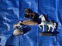 Top view of three horse figurines on blue tarp showing bases and condition