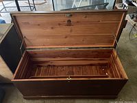Open cedar wood chest showing interior wooden slats and push button lid mechanism.