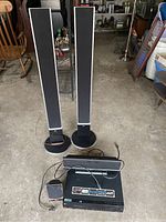 Full view of LG sound system components including base unit, four speakers, and cables on a floor