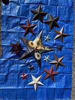 All 13 metal stars of various sizes and designs laid out on blue tarp for size and color visibility