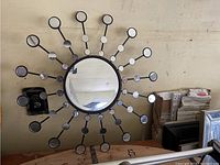 Front view of the starburst mirror showing concentric circles of smaller mirrors around central mirror on black metal frame