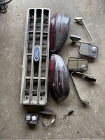 Photo of front showing the Ford grill, two vintage red taillights, two side mirrors, and a metal charge monitor device with wiring.