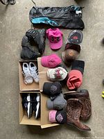Top down photo of assorted footwear and hats arranged on floor showing various brands and colors