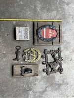 Top down view of six decor pieces on concrete floor, showing varying sizes with measuring tape for scale. Items include hooks, bottle opener, picture frame, and plaque.