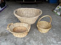 Three different sized woven baskets placed on floor, showing front and side views