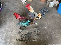 Top-down view of all metal bird weathervanes and horse weathervane base together on the ground