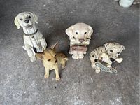 Four dog statues placed on cement floor including two with welcome signs and two without.