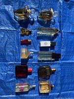 Overview of ten assorted perfume and cologne bottles laid out on blue tarp.