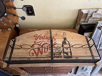Wooden wine rack with metal bottle holders and vintage wine graphic on front.