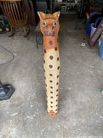 Front view of tall spotted wooden cat sculpture showing face, eyes, nose, mouth and spotted pattern on front.