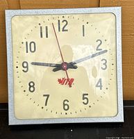 Front view of one square vintage wall clock showing clock face with the ITR logo, black numerals, black hour and minute hands, and red second hand under curved glass.