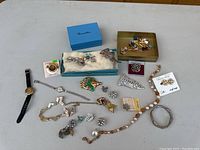 Overview of assorted costume jewelry and watches including boxes, earrings, brooches, necklaces, and bracelets.