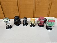 Front view of six Funko Star Wars droid figures on a flat surface against wood panel background.