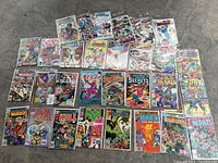 Top down photo of 31 comic books arranged lying flat, showing front covers with various titles and artwork
