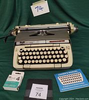 Smith Corona typewriter front view with ribbon, manual, and carrying case arranged below