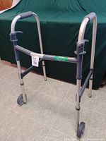 Full frontal view of the collapsible walker showing padded handles, front wheels, and rear rubber tips.