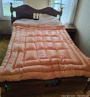 Orange gold satin down duvet throw laid out on bed showing size and condition.
