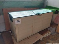 Beige garden storage box with green top lid, showing overall condition and measurements notes.