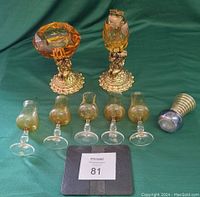 Full set of cut glass lighter and ashtray, six liqueur glasses, and small striped glass item on a green cloth background.
