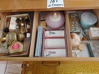 Top-down view of two open dresser drawers filled with vintage Avon perfume bottles, Palmolive soap, boxed soaps, and a purple glass lidded candy dish.