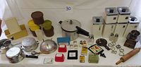 Photo showing the full spread of retro kitchen items including pressure cooker, Tupperware containers, coffee grinder, metal tins, colanders, rolling pin and more.