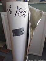 Roll of reflective insulation paper standing upright with visible wear and peeling on reflective side.