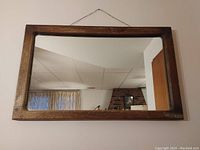 Overall view of vintage wooden rectangular mirror hanging on a wall.