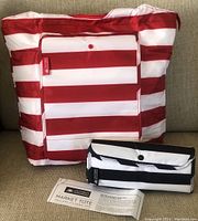 Photo showing large red and white striped insulated foldable tote bag with front snap pocket and smaller black and white striped foldable insulated tote bag. Includes product information card for California Innovations Market Tote.