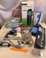 Full lot arranged on flat surface showing all items including UV sterilization pump, hardware screws, fittings, a tool bar, and metal lever assembly.