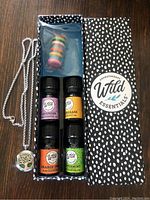 Full contents of the essential oils necklace kit with four essential oil bottles, pendant necklace, and felt balls container visible in original box.