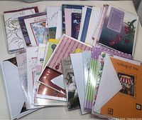 Image showing assorted greeting cards stacked on a flat surface, displaying various designs including floral and seasonal themes.