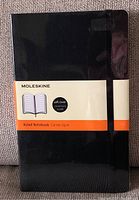 Front cover of the new black Moleskine notebook showing soft cover and band closure.