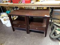 Photo showing both casual end tables side by side, made of dark stained wood with drawers and shelves.