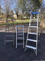 Photo displaying all three ladders together showing size and condition: wooden, Keller aluminum folding ladder, and Werner aluminum step ladder.