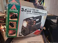 Photo of the Alltrade 3-in-1 air compressor box showing product model and features including 12 volt power and 220 PSI pressure capacity.