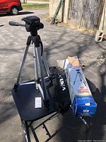 Full view of tripod standing on a black folding table outdoors, with the Vista box and a black carrying bag visible beside it.