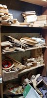 Shelves full of stacked unfinished wood sheets, blocks, and cut pieces organized in a storage area