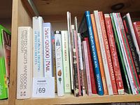 Shelf of diverse hardback and paperback books with topics in electronics, crafts, travel, and American history.