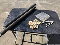 Pair of large black garage door springs, two mouse traps, small metal springs in plastic bag, and plastic spring mouse eliminators on black table