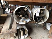 Three white buckets holding assorted metal trowels with wooden handles, different notch depths visible inside buckets.