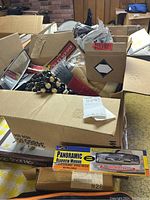 Photo of cardboard boxes containing assorted automotive products including rearview mirror packaging and other items inside boxes