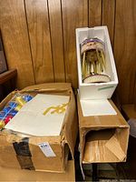 Cardboard box containing vintage glass Christmas tree ornaments, some blue and red colors, stored in packaging in basement setting.