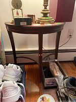 Full view of wood demilune table with shoes and items around it, showing overall condition and shape.
