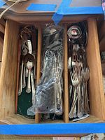 Drawer with organized Ekco Classic Crest flatware and serving utensils, separated in wooden compartments.