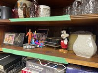Wooden shelf with Elvis Presley figurine, vintage clock, Mickey Mouse figurine, keepsake box, Lenox vase, crystal glasses, ceramic mugs