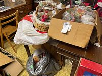 Wicker basket close-up with Santa figurine seated among miniature decorative Christmas trees and snowflake accents.