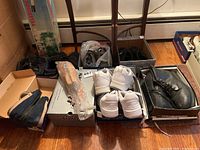 Overview photo showing multiple pairs of men's shoes including Adidas sneakers, black dress shoes, boots, and Skechers shoes arranged in their boxes and on the floor.