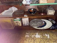 Multiple vintage serving ware pieces including platters and bowls on wooden shelves